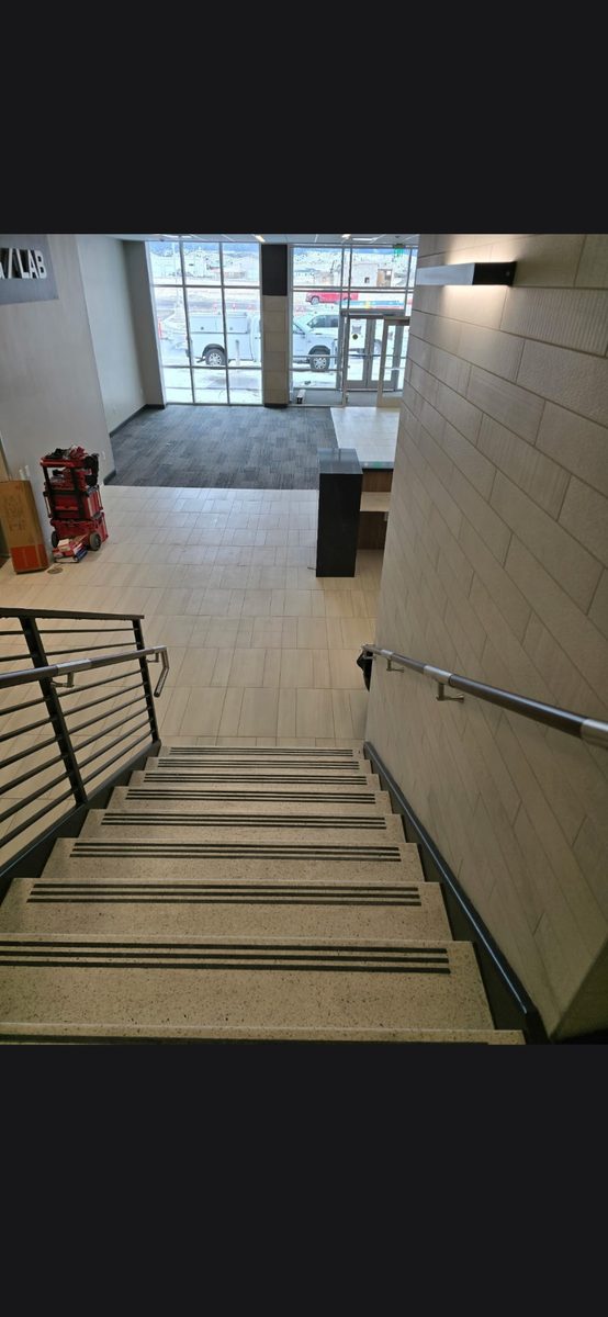 Commercial stairwell with tiled treads, nosing strips and a stone-look feature wall