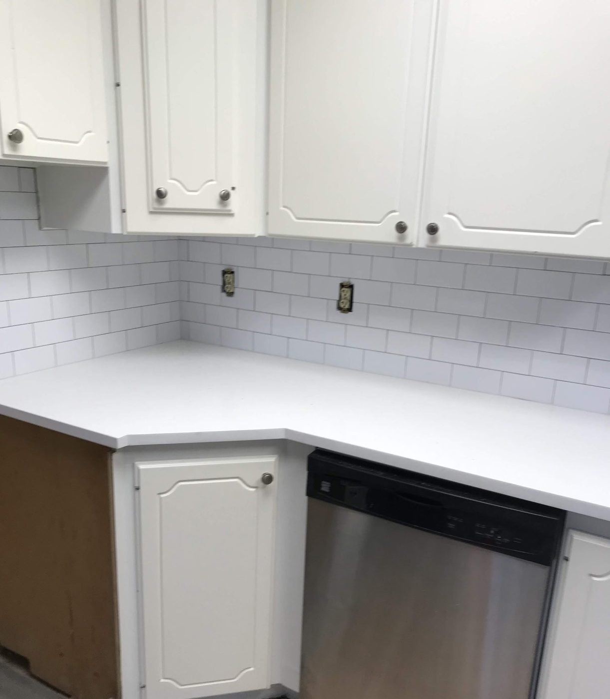 Finished white subway tile kitchen backsplash above white cabinets