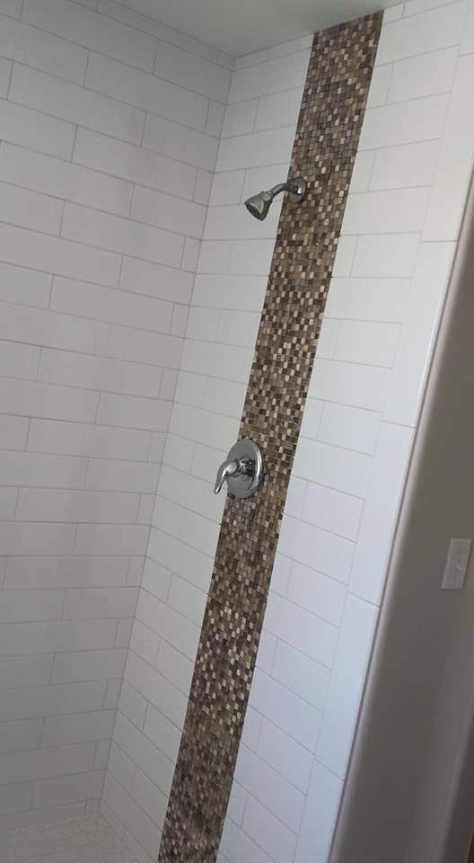 Finished white subway tile shower with a vertical pebble mosaic stripe
