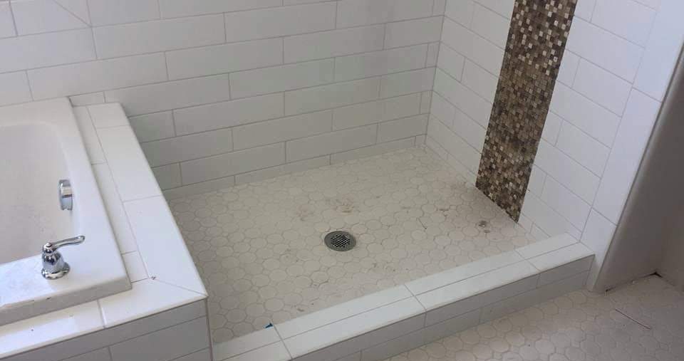 Finished tub and shower surround in white subway tile with a pebble accent band