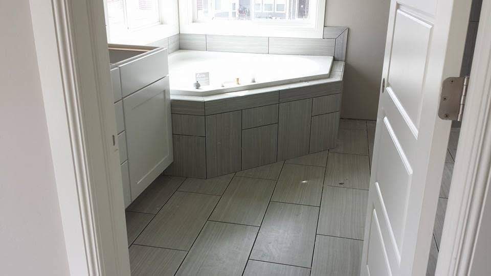 Finished corner garden tub surround with a plank tile floor